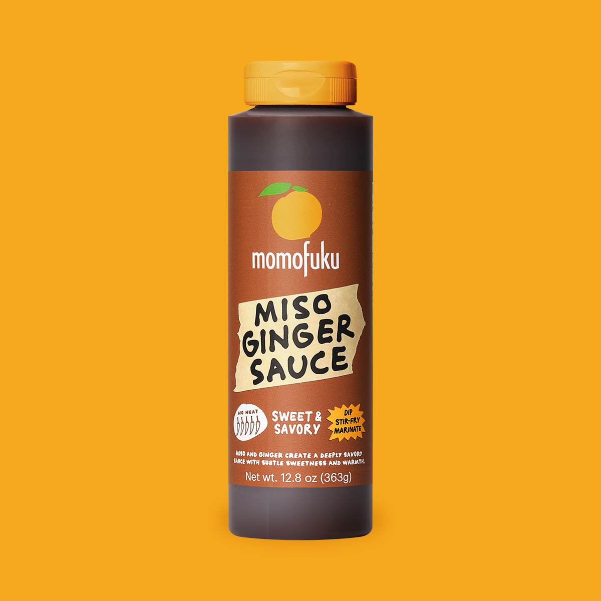A bottle of Momofuku Miso Ginger Sauce centered on a solid orange-yellow background. The bottle is dark brown with a yellow cap and a brown label featuring the brand name 'momofuku' and the product name 'MISO GINGER SAUCE'.