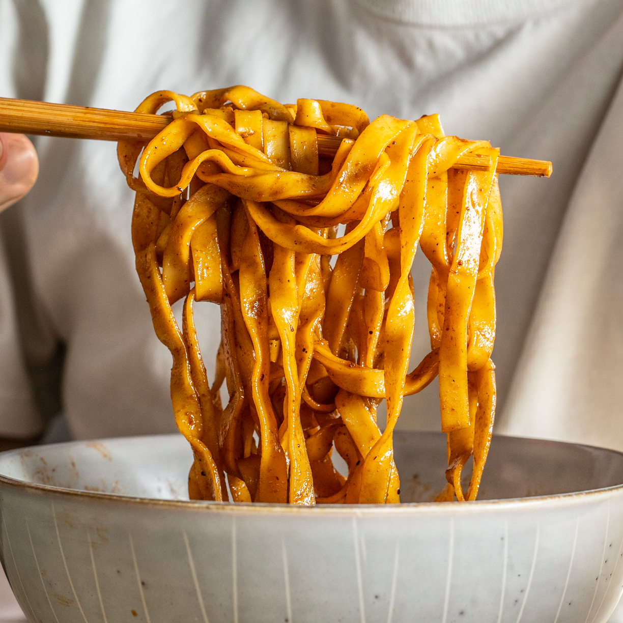 Noodles on chopsticks pulled from a bowl